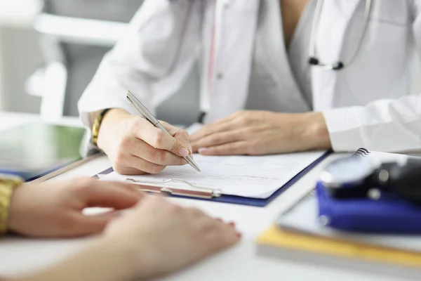 Medico scrivere informazioni in documenti di fronte al paziente in primo piano clinica — Foto Stock