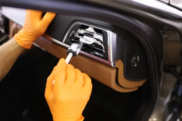 Professioneller Autoservice-Mitarbeiter in Schutzhandschuhen reinigt Autogrill mit Schaum und Bürste — Stockfoto