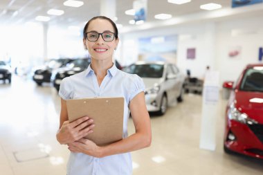 Kadın yönetici danışmanı araba galerisinde duruyor.