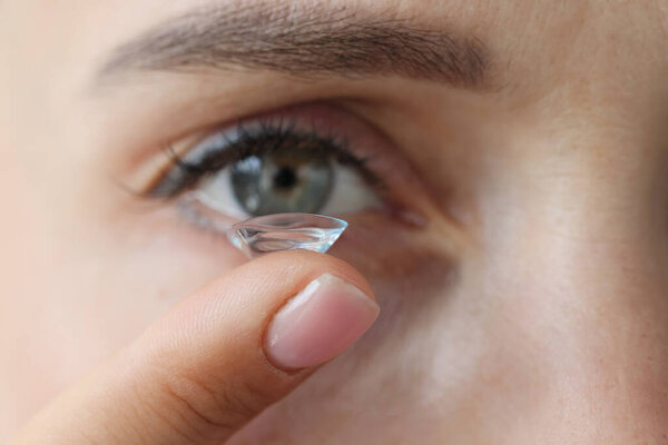 Young woman putting on contact lenses closeup