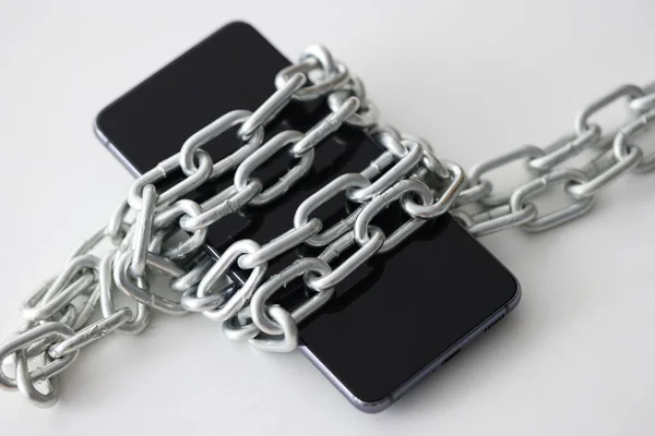 Black smartphone wrapped in metal chain closeup — Stock Photo, Image