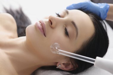 Doktor, Darsonval 'ın yardımıyla hastaya yüz masajı yapıyor.