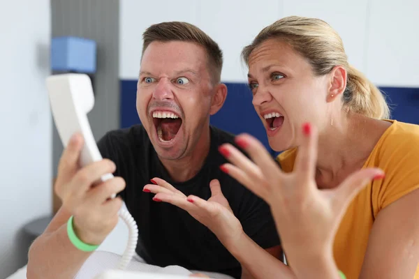 Man en vrouw schreeuwend in telefoonhoorn in hotelkamer — Stockfoto
