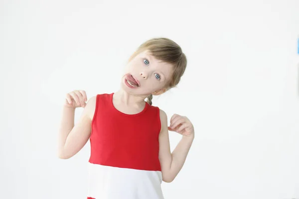 En liten rolig flicka som skojar och visar tungan. — Stockfoto