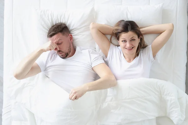 침대에 누워 있는 부부. 사람 이손으로 코를 막고 있다 — 스톡 사진