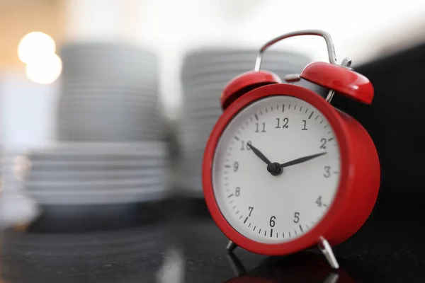 Red alarm clock on background of large stack of plates — Stock Photo, Image