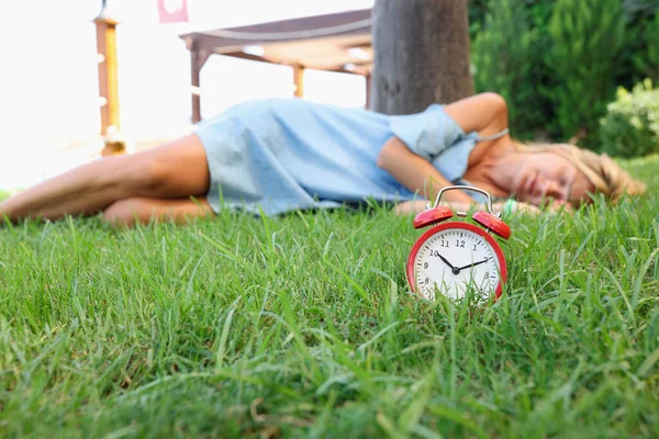 Kobieta śpi na trawie obok budzika — Zdjęcie stockowe