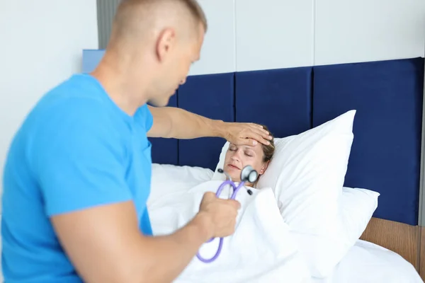 Dokter voert medisch onderzoek van zieke vrouw in bed — Stockfoto