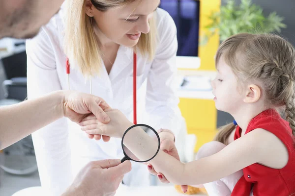 Médico examinando a pele do bebê na mão com lupa na clínica — Fotografia de Stock