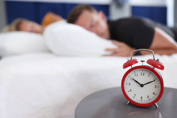Άνδρες και γυναίκες κοιμούνται στην κρεβατοκάμαρα με ξυπνητήρι στις 10 το πρωί. — Φωτογραφία Αρχείου