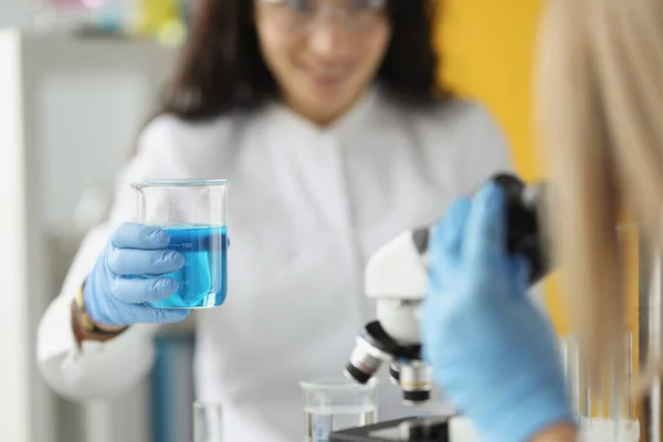 Lékařský nebo vědecký vědec žena při pohledu na zkumavky s čirým modrým roztokem v laboratoři — Stock fotografie