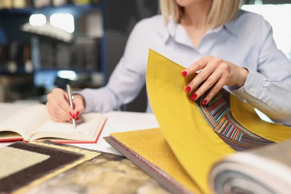 Mujer elige la tela con patrón para la tapicería en el interior de la tienda —  Fotos de Stock