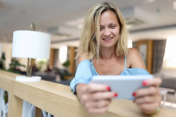 Glimlachende vrouw houdt smartphone en kijkt naar het scherm — Stockfoto