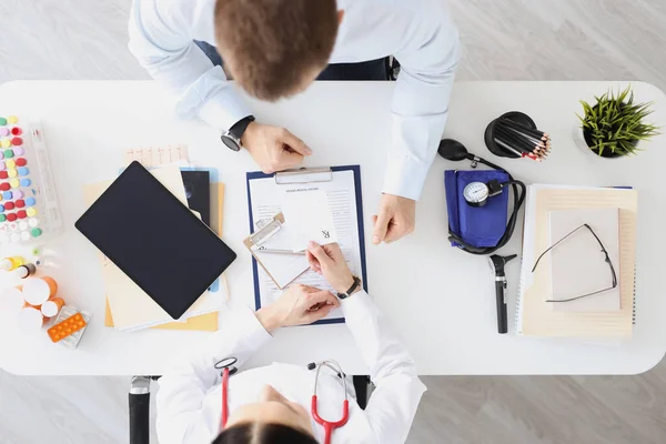 医者はテーブルに座り 患者の上の眺めに処方箋を書いています 医療の概念 — ストック写真