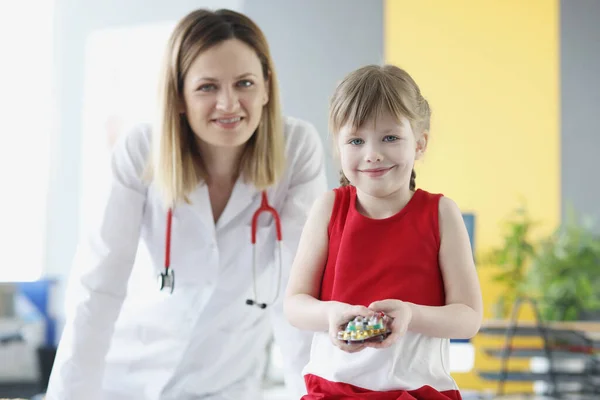 Pediyatrist doktor ve küçük kız ellerinde tıbbi haplar tutuyorlar. — Stok fotoğraf