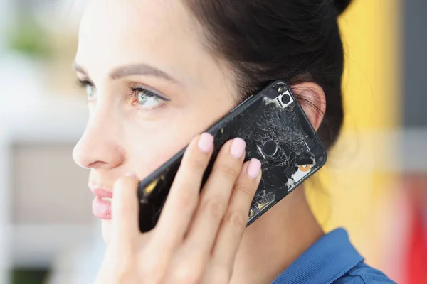 Woman is talking on broken black smartphone closeup — Stock Photo, Image