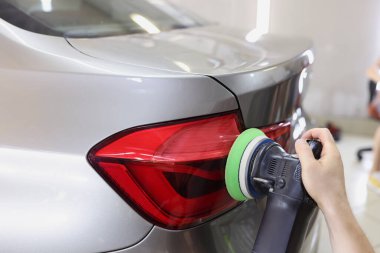 Özel makineyle araba cilalayan bir tamirci.