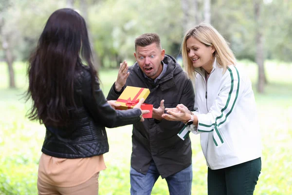 Femme donnant cadeau en boîte rouge jeune couple dans le parc — Photo