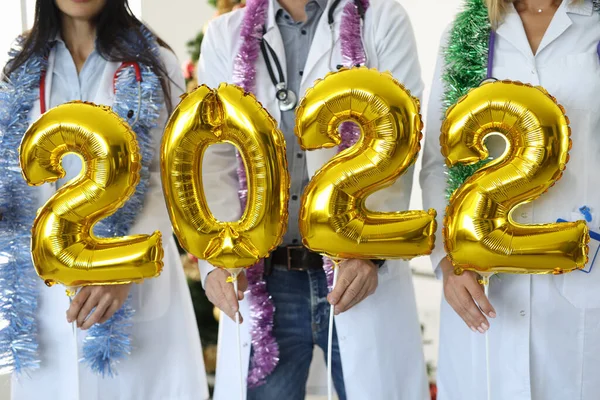 Doctors holding golden balloons with numbers 2022 closeup