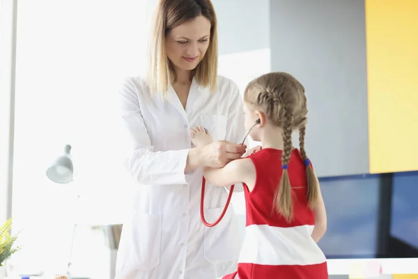 Lekarz pediatra zakładający stetoskop małej dziewczynce w klinice — Zdjęcie stockowe