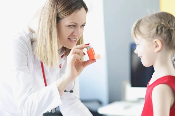 Pneumologista médico segurando inalador hormonal na frente da menina na clínica. — Fotografia de Stock