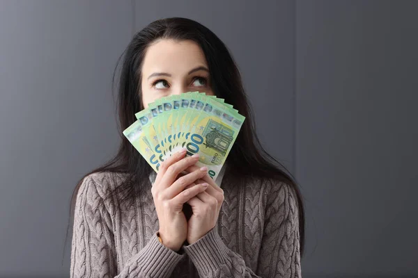 Jovem mulher pensativa segurando lotes de notas de euro na frente dela — Fotografia de Stock