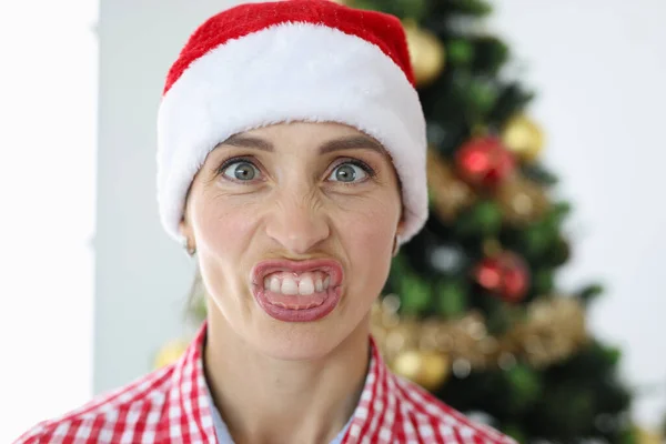 Portret van geïrriteerde vrouw in kerstman hoed op de achtergrond van kerstboom — Stockfoto