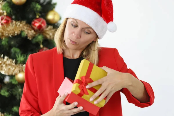 Жінка в червоній куртці і капелюх Санти Клауса дивиться в подарункову коробку — стокове фото