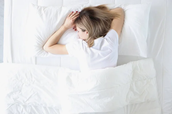 Молода жінка спить на животі в білому ліжку вид зверху — стокове фото