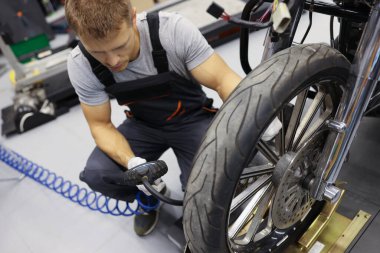 Otomobil tamirhanesinde motosiklet lastiklerini şişiren bir adam.