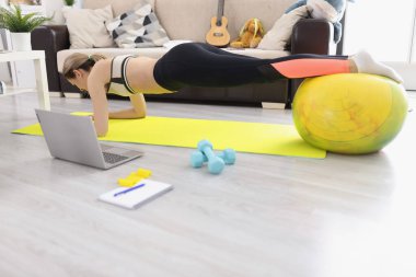 Genç atletik kadın evde kalas kullanıyor.