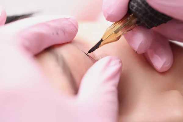 Master make-up kunstenaar maakt permanente make-up voor een klant oogleden — Stockfoto