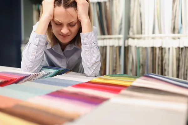 Woman painfully thinks about which fabric to choose in store — Stock Photo, Image