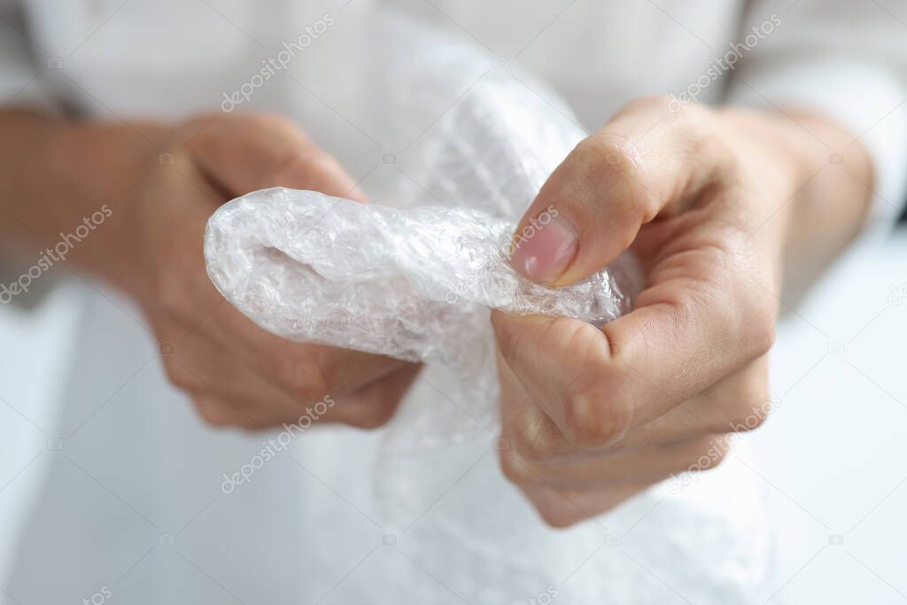 Female hands crush bubble plastic bag closeup