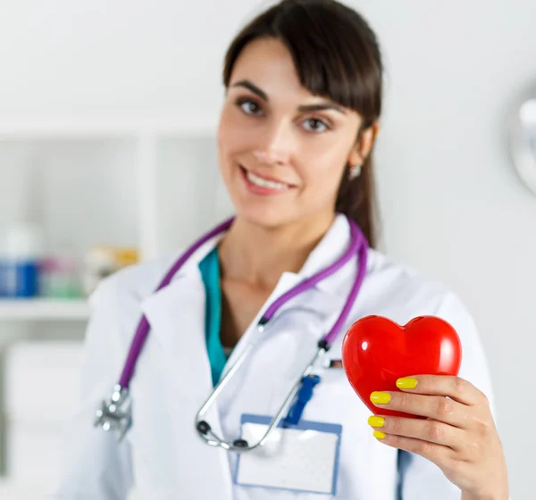 美しい笑顔の女性の医師は胸の前に赤いハートを保持しています。医療のヘルプ、予防法、保険、手術と蘇生のコンセプトです。心臓病、健康、保護・予防 — Stock fotografie