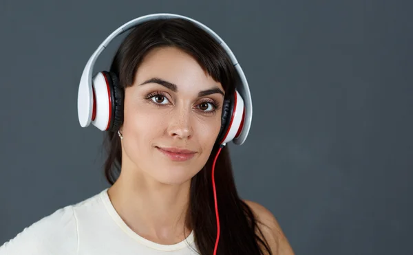 Piękne ciemne włosy kobieta uśmiechający się noszenie słuchawek — Zdjęcie stockowe