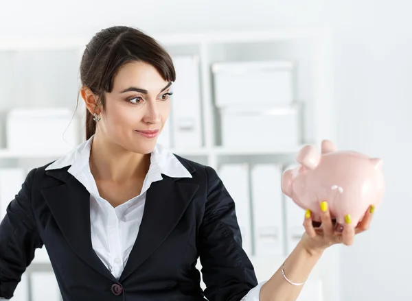 Happy and mysterious beautiful woman holding funny piggybank in — Zdjęcie stockowe