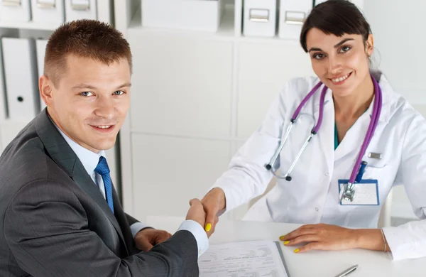 Hermosa mujer sonriente médico de medicina estrechando la mano con el hombre —  Fotos de Stock