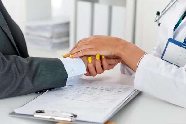 Amistosas manos de doctora sosteniendo la mano de paciente masculino —  Fotos de Stock