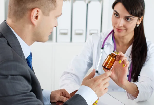 Beautiful female medicine doctor giving pills to male patient — Stok fotoğraf