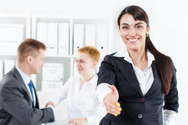 Beautiful smiling business woman in suit offering hand to shake — Stockfoto