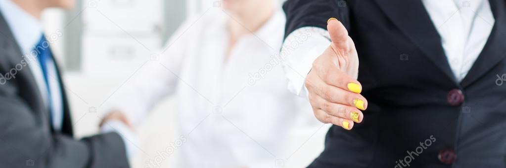 Beautiful smiling business woman in suit offering hand to shake