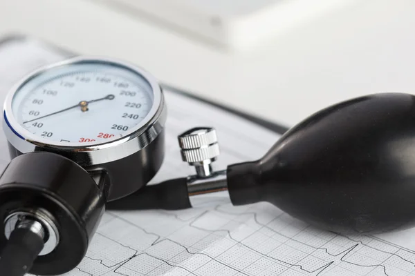 Медицинский манометр, лежащий на кардиограмме крупным планом — стоковое фото