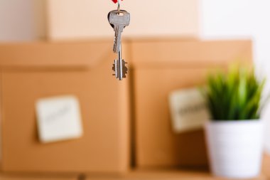 Female hand holding keys over pile of brown cardboard boxes