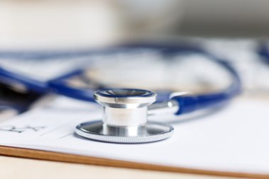 Prescription form clipped to pad lying on table with stethoscope