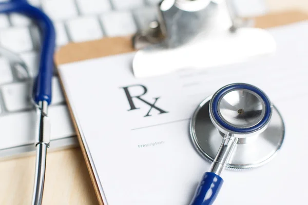 Prescription form clipped to pad lying on table with keyboard an — Stockfoto