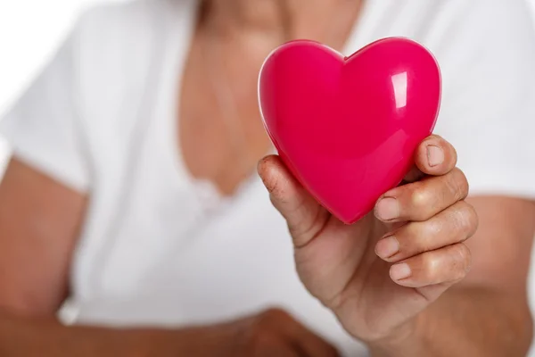 Oudere vrouw met rode speelgoed hart voor haar borst — Stockfoto