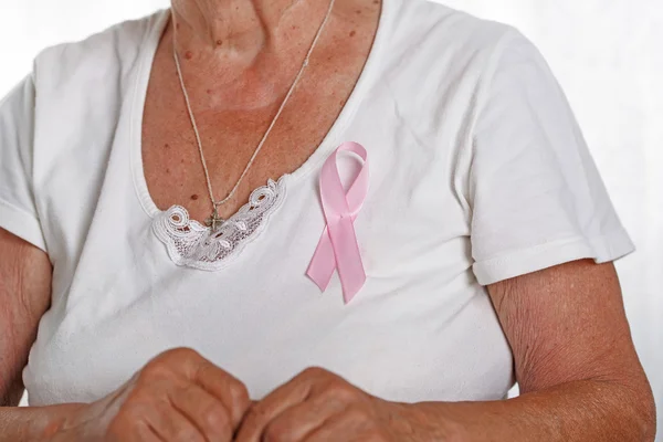 Petto della donna anziana con appuntato rosa consapevolezza cancro al seno ri — Foto Stock