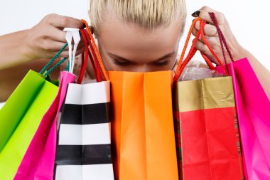 Blond woman inspecting content of colored paper bags with fresh 