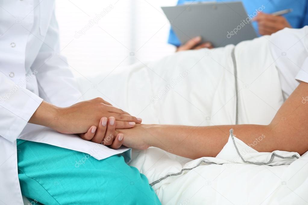 Friendly female doctor's hands holding patient's hand 